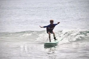 Kid standing on a surfboard during a surfing for beginners lesson in Arugam Bay, learning to ride waves with Arugambay Agenda