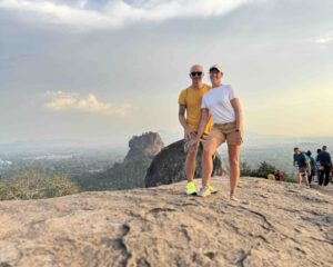 Couple standing on Pidurangala Rock with Sigiriya Lion Rock in the background during a Sigiriya tour from Arugambay, capturing scenic views of Sri Lanka’s iconic landmark